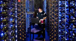 Google’s Denise Harwood replaces a CPU amid the blue-lit server-packed racks in the company’s data center in The Dalles, Oregon. (Photo: Google)